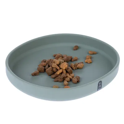 Bol rotund, verde pentru hrană, cu bucăți de hrană uscată. Bol din material neted, logo-ul mărcii 'Tia' vizibil pe margine.