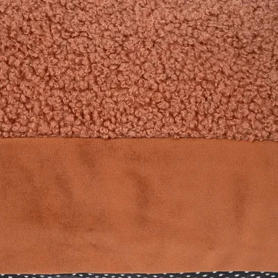 Gros plan sur une surface en tissu bouclé marron et une bande en tissu lisse marron, avec un bord inférieur à pois blancs sur fond noir. Matériaux visibles : tissu.