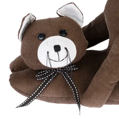 Barna textil játék macska formában, gombszemekkel, fehér arccal és pöttyös masnival.