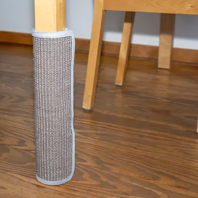 Kratzschutz aus grauem Sisalstoff, um ein Tischbein gewickelt. Schutz für Möbel vor Kratzspuren.