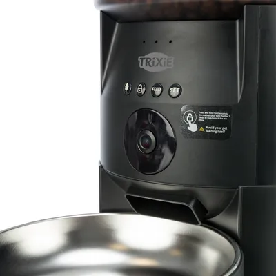 Trixie voerautomaat met camera, microfoon, knoppen voor Feed en Set en roestvrijstalen voerbak. Opmerking: knop ingedrukt houden om de vergrendeling te deactiveren.
