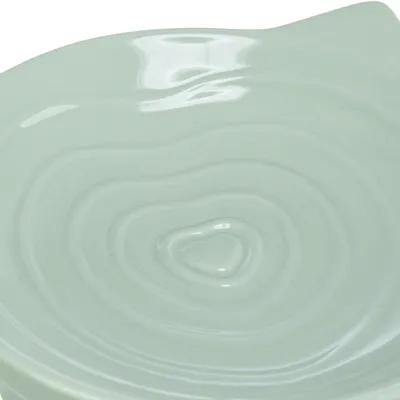 Prim-plan cu un bol din ceramică verde deschis, cu design ondulat și suprafață lucioasă.