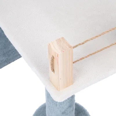 Plateforme recouverte de tissu blanc avec poteaux en tissu bleu, bloc en bois clair et cordes en sisal visibles sur le coin, éléments d’un arbre à chat.