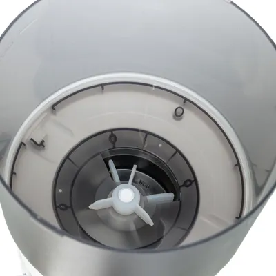 Binnenkant van een transparante kunststof voerautomaat met maataanduidingen en een plastic verdeelmechanisme zichtbaar.