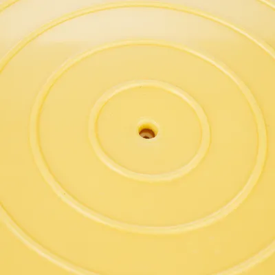 Disco di plastica gialla con cerchi concentrici e foro centrale, possibile parte di un gioco o accessorio.