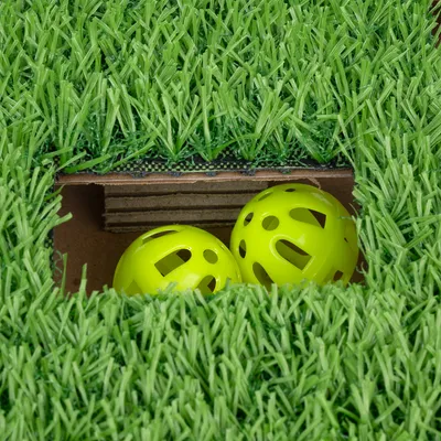 Green plastic grass mat with cut-out, two yellow plastic play balls visible underneath.