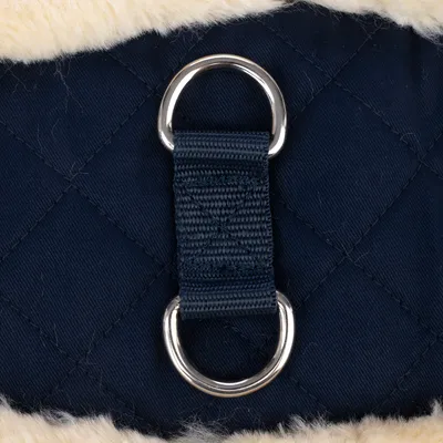 Close-up van donkerblauwe, gewatteerde stof met twee zilverkleurige metalen ringen en een stevig nylon band. Bovenrand van crèmekleurige imitatiebont.