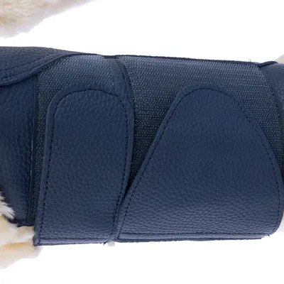 Vue rapprochée d’une sangle en similicuir bleu avec fermeture auto-agrippante sur pelage clair, montrant la texture du matériau et le système de fixation.