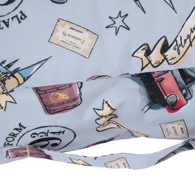 Détail d’un tissu imprimé avec motifs Harry Potter : chapeau, livre, billet Platform 9 3/4, étoiles et parchemins. Poignée en tissu assorti visible au premier plan.
