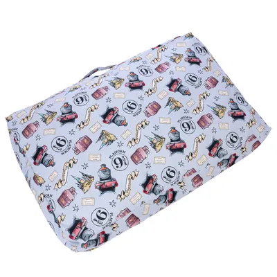 Coussin rectangulaire avec housse à motifs Harry Potter : Platform 9 3/4, châteaux, valises, trains rouges et parchemins. Poignée visible sur le dessus.