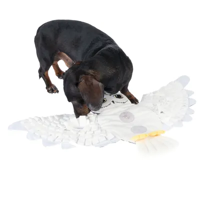 Hund spielt mit einer weissen Eulen-Schnüffelmatte, die aus Stoff besteht und verschiedene Texturen sowie versteckte Taschen bietet.
