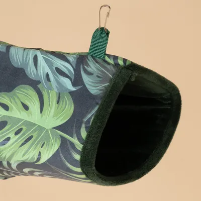 Cueva colgante con estampado de hojas tropicales, borde verde y gancho metálico para fijación.