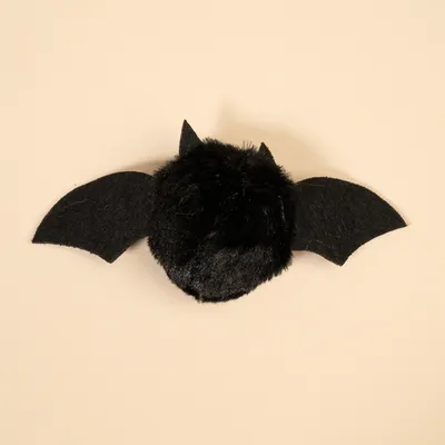 Musta lelu lepakon muodossa, pörröinen vartalo ja huopasiivet.