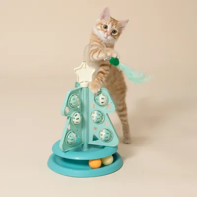 Chat tigré debout jouant avec un arbre à chat interactif turquoise, équipé de balles et d’un pompon suspendu à une étoile au sommet. Jouet en plastique pour chat visible en entier.
