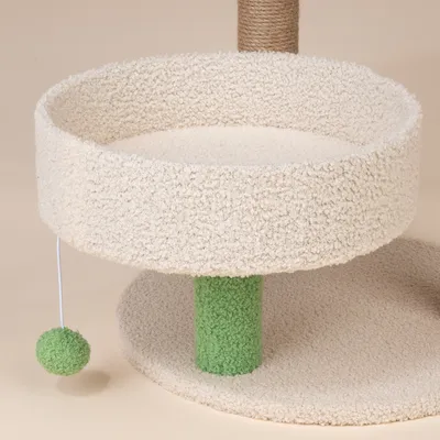 Drapak z beżowym pluszowym legowiskiem, zielonym słupkiem i wiszącą zieloną piłką do zabawy.