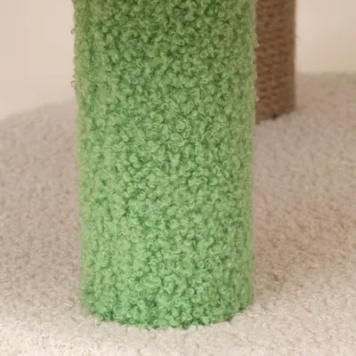 Zielony drapak pokryty miękką tkaniną na jasnej platformie. W tle widoczny kolejny drapak w naturalnym kolorze.