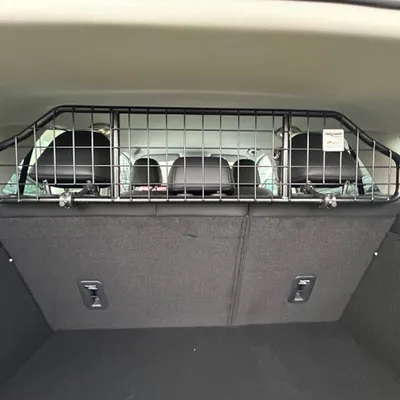Metall-Trenngitter für Autos, schwarz, montiert zwischen Kofferraum und Rücksitzen. Sichtbar: Kopfstützen der Sitze und Befestigungselemente des Gitters.