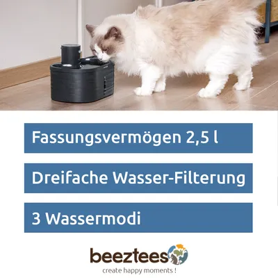 Chat buvant à une fontaine noire. Texte en allemand : Fassungsvermögen 2,5 l, Dreifache Wasser-Filterung, 3 Wassermodi. Marque beeztees visible.