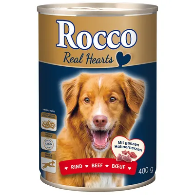 Blik Rocco Real Hearts hondenvoer, rund, 400 g. Tekst: 'extra grote vleeschunks', 'vers vlees 100%', 'kracht & energie'. Beeld van hond en stukjes vlees op het etiket.