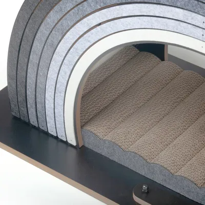 Kratzmöbel aus Wellpappe mit gewölbtem Design und grauen Filzstreifen, geeignet für Krallenpflege.