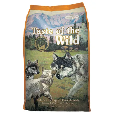 Balení s textem Taste of the Wild, High Prairie Puppy Formula with Roasted Venison & Bison, A Grain-Free Diet, Purified Water. Ilustrace vlků na louce.