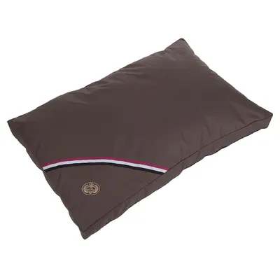 Coussin rectangulaire marron avec bande décorative rouge, blanche et noire et écusson rond cousu dans un coin. Matière textile visible.