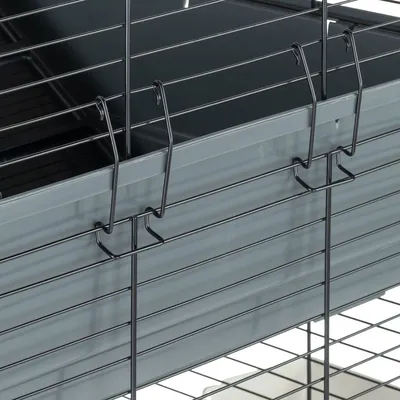 Detailansicht eines grauen Metallkäfigs mit Gitterwänden und Haken zur Befestigung. Innenbereich des Käfigs teilweise sichtbar.