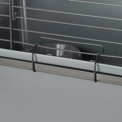 Close-up view of a cage with metal mesh walls and a grey food bowl inside.