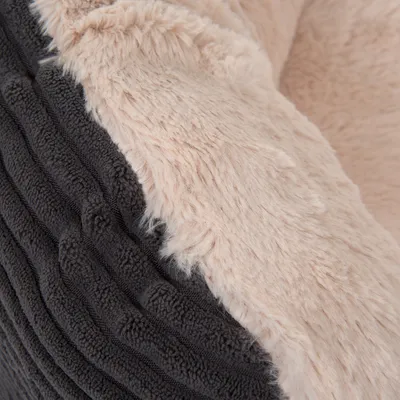 Lähikuva lemmikkisängystä, jossa on pehmeä beige plyysi ja ribattu tummanharmaa kangas.