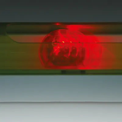 Rotes LED-Licht in einem transparenten Gehäuse, möglicherweise Teil eines Spielzeugs oder Zubehörs.