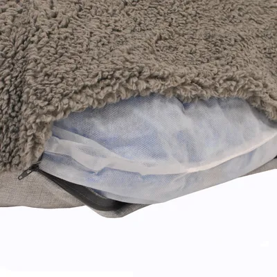 Detailansicht eines grauen Tierkissens mit abnehmbarem Bezug und sichtbarer Innenfüllung aus Netzmaterial.