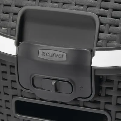 Close-up of a black clasp with sliding mechanism and Curver logo on a woven surface.