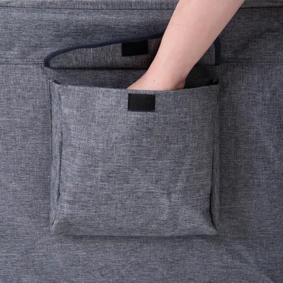 Hand greift in eine graue Stofftasche mit Klettverschluss, befestigt an einem Möbelstück.