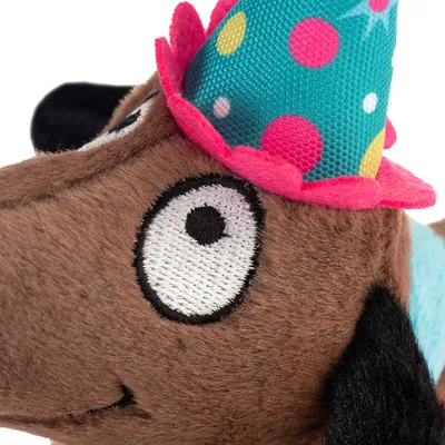 Plush toy shaped like a brown dog with a party hat, multicoloured spots and a pink border.