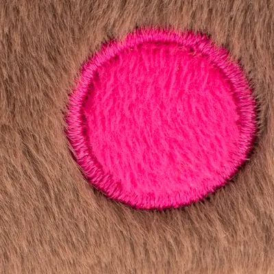 Close-up of brown fur material with a round pink patch in the centre.