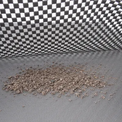 Primer plano de arena para gatos sobre una superficie gris y texturizada con un fondo a cuadros.