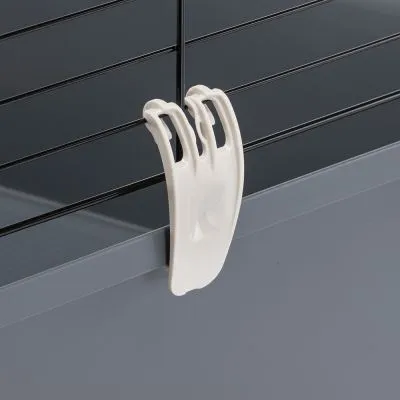 Gancio in plastica bianca fissato su una gabbia con sbarre metalliche nere e base grigia, dettaglio del sistema di chiusura o blocco visibile.