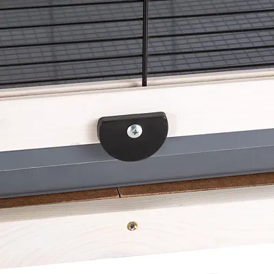 Close-up of a black fastener on a wooden frame with metal grid.