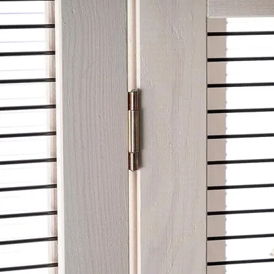 Close-up view of a wooden frame with metal hinge and black bars.