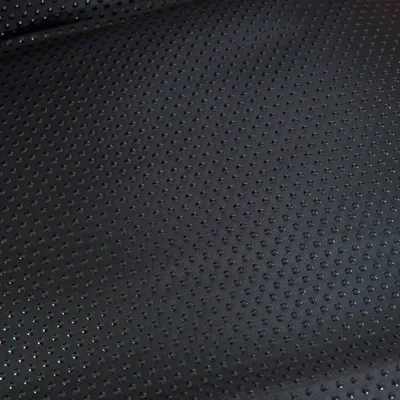 Close-up of black perforated material with small holes, suitable for breathable surfaces.