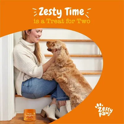 Person sitting on stairs with a dog, product container nearby. Text reads: 'Zesty Time is a Treat for Two'. Zesty Paws branding visible.