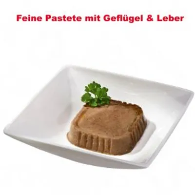Feine Pastete mit Geflügel & Leber. Färskt foder i form av pastej på vit tallrik, dekorerad med persilja. Texten är på tyska.