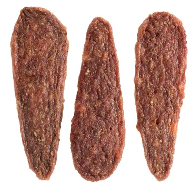 Três snacks para cães alongados e castanhos com textura carnuda, visíveis sem embalagem.