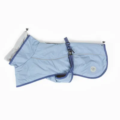 Manteau pour chien bleu clair avec doublure grise, sangle réglable et boucle, badge rond marqué 'NF' visible sur le côté.