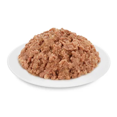 Aprított, barna színű nedves állateledel fehér tányéron, mártásban tálalva. Csomagolás vagy márkanév nem látható.