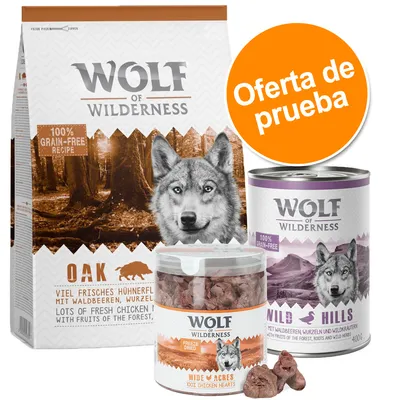 Wolf of Wilderness oferta de prueba: saco Oak 100% grain-free, bote Wild Acres corazones de pollo liofilizados, lata Wild Hills. Textos en inglés y alemán visibles en los envases.