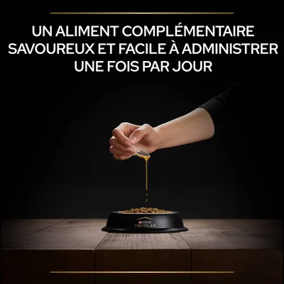 Texte : Un aliment complémentaire savoureux et facile à administrer une fois par jour. Main versant un liquide sur des croquettes dans une gamelle Purina Pro Plan.