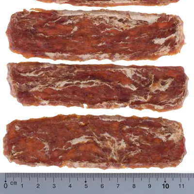 Négy hosszúkás kutyacsemege barna és fehér erezettel, egymás mellett elrendezve. Az alsó mérce kb. 10 cm hosszúságot mutat.