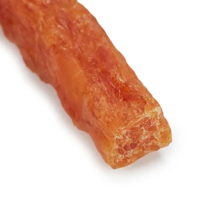 Bliski prikaz narančastog, sušenog snacka izduženog oblika. Detalji o sastavu ili upotrebi nisu vidljivi.