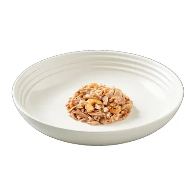 Порция консервирана храна за домашни любимци, сервирана в бяла керамична купа. Видими парчета месо и морски дарове.